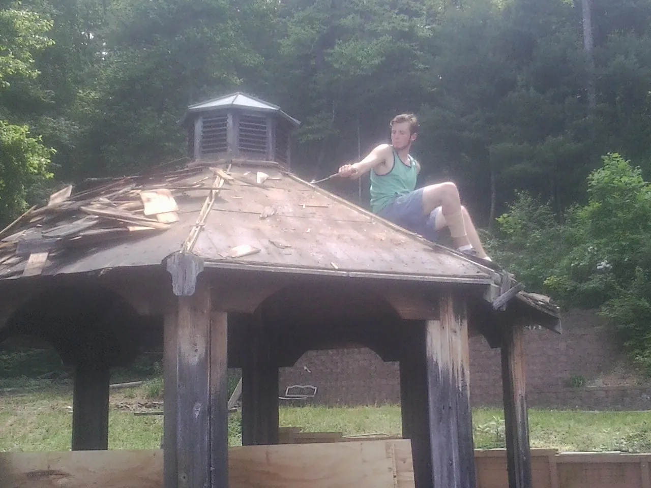 Tearing the old roof off a wooden gazebo before new shakes in Brayton