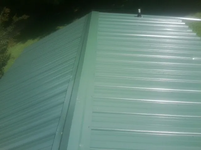 New green metal panels meeting at the ridge of a roof — Flat Roof Repair work by our crew in Brayton
