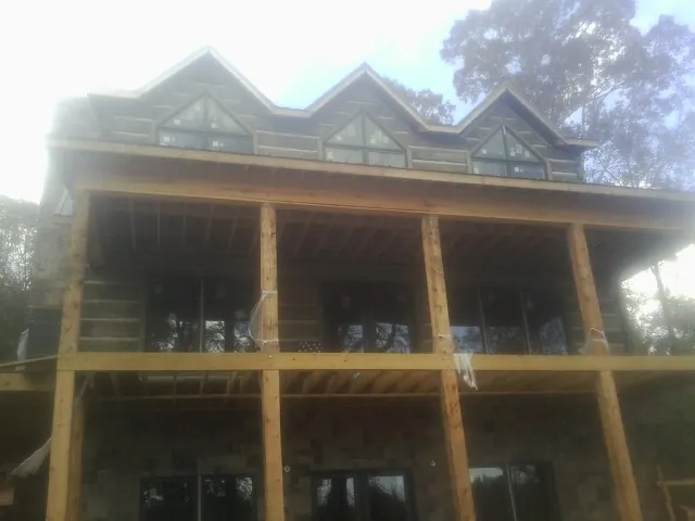 Dormers and porch framing on a large log home under construction — Roof Coating work by our crew in Brayton