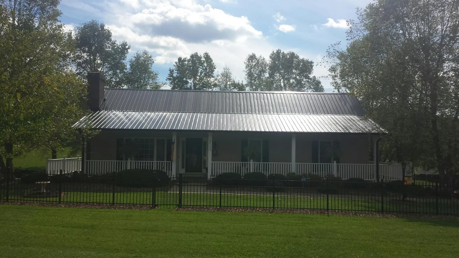 Gray metal roof on a brick ranch with a full width front porch — Gutter Guard Installation work by our crew in Brayton