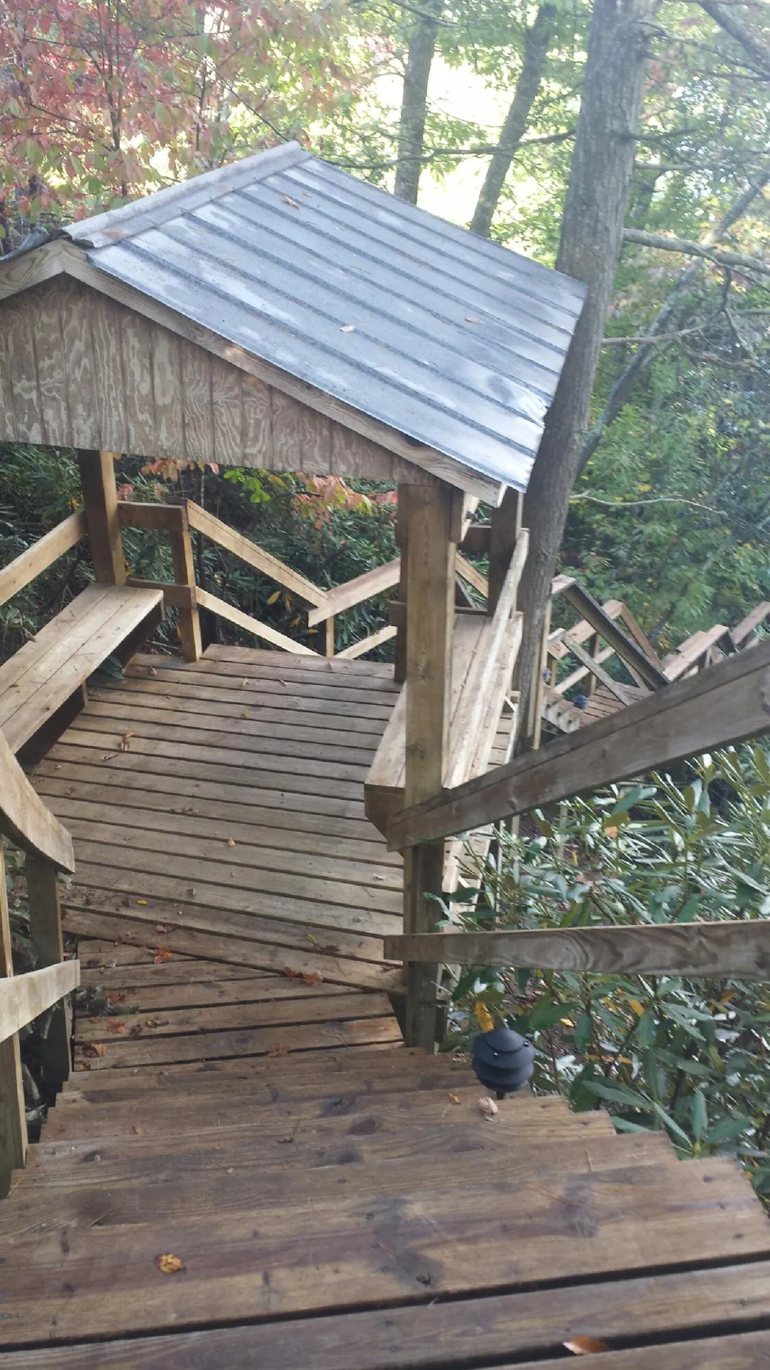 Metal roofed shelter over wooden steps on a wooded walkway — Skylight Repair & Installation work by our crew in Brayton
