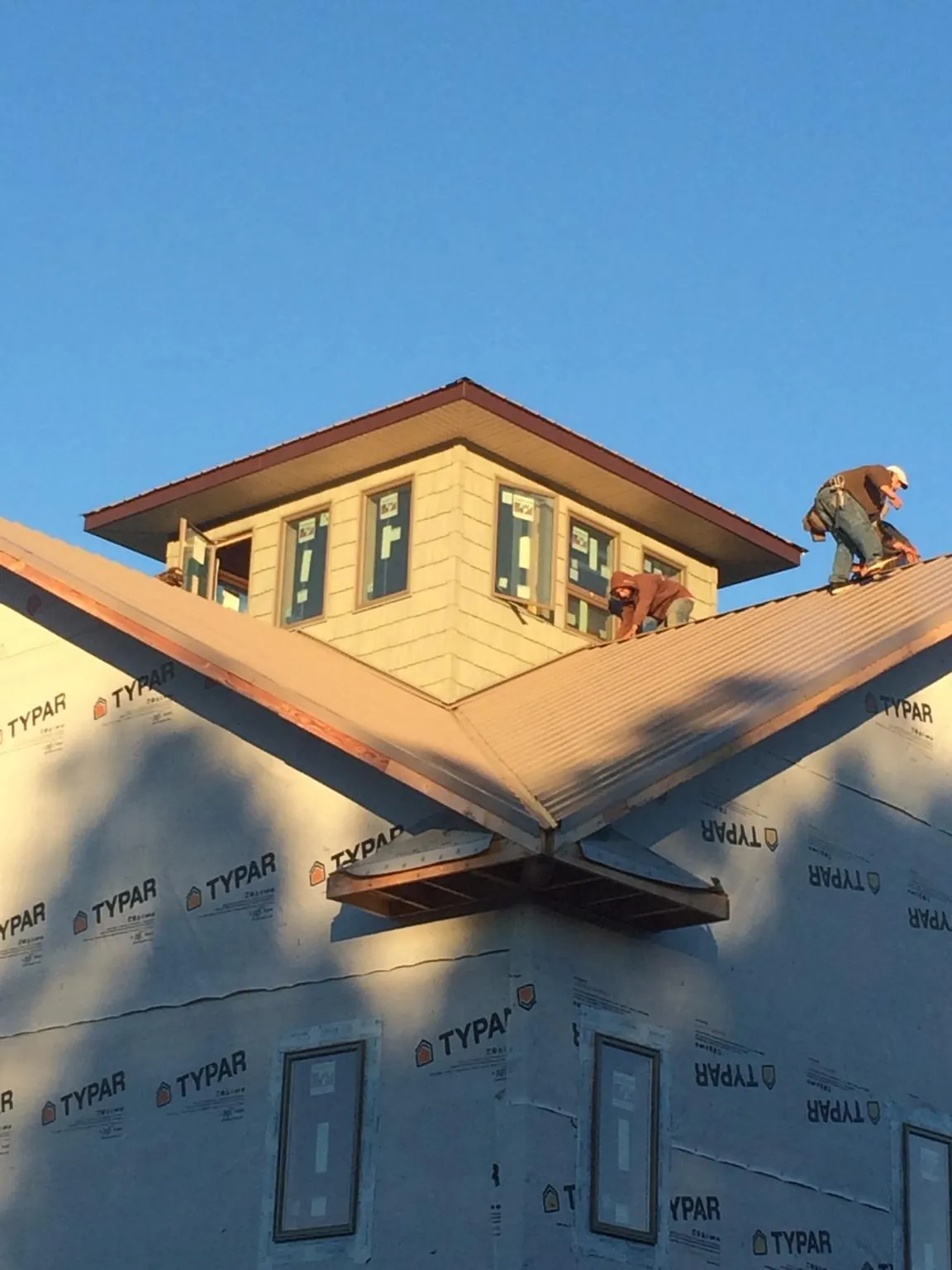 Roofers working around a rooftop cupola on a new metal roof at sunset — Roof Waterproofing in Brayton by Roofing Brothers